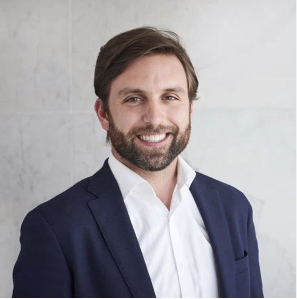 Smiling brown haired man with beard in blue suit and white shirt