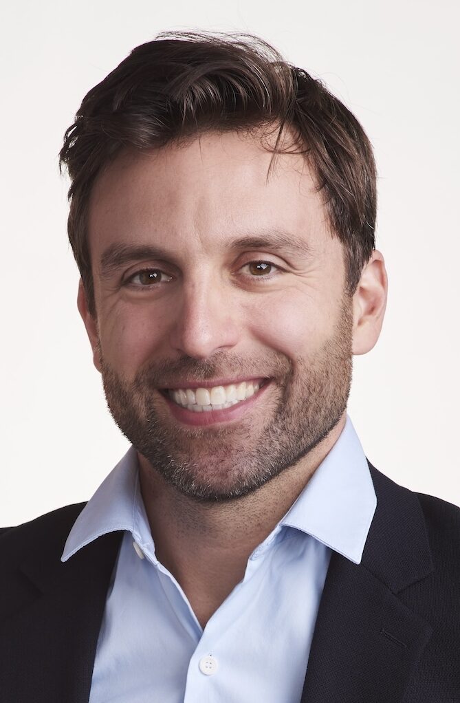 Headshot of man in blue shirt with beard