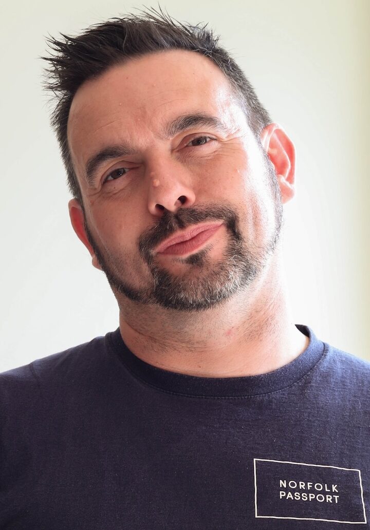 Man with dark hair and small beard in navy tshirt