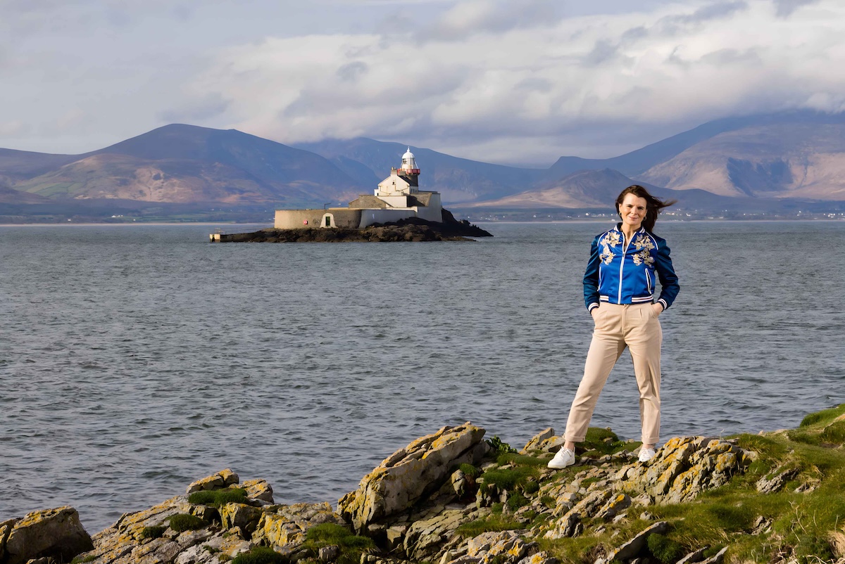 Woman stood on a cliff with the ocean behind her