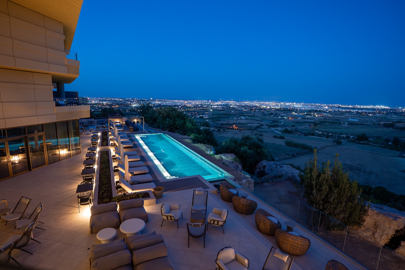 An outdoor pool in a hotel by night