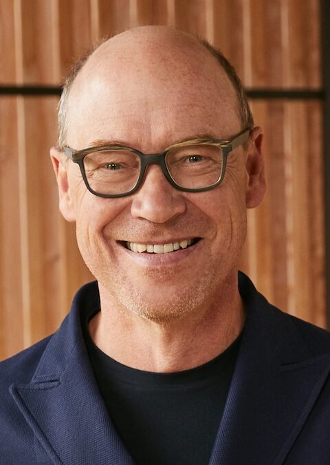 Headshot of smiling man in glasses with no hair
