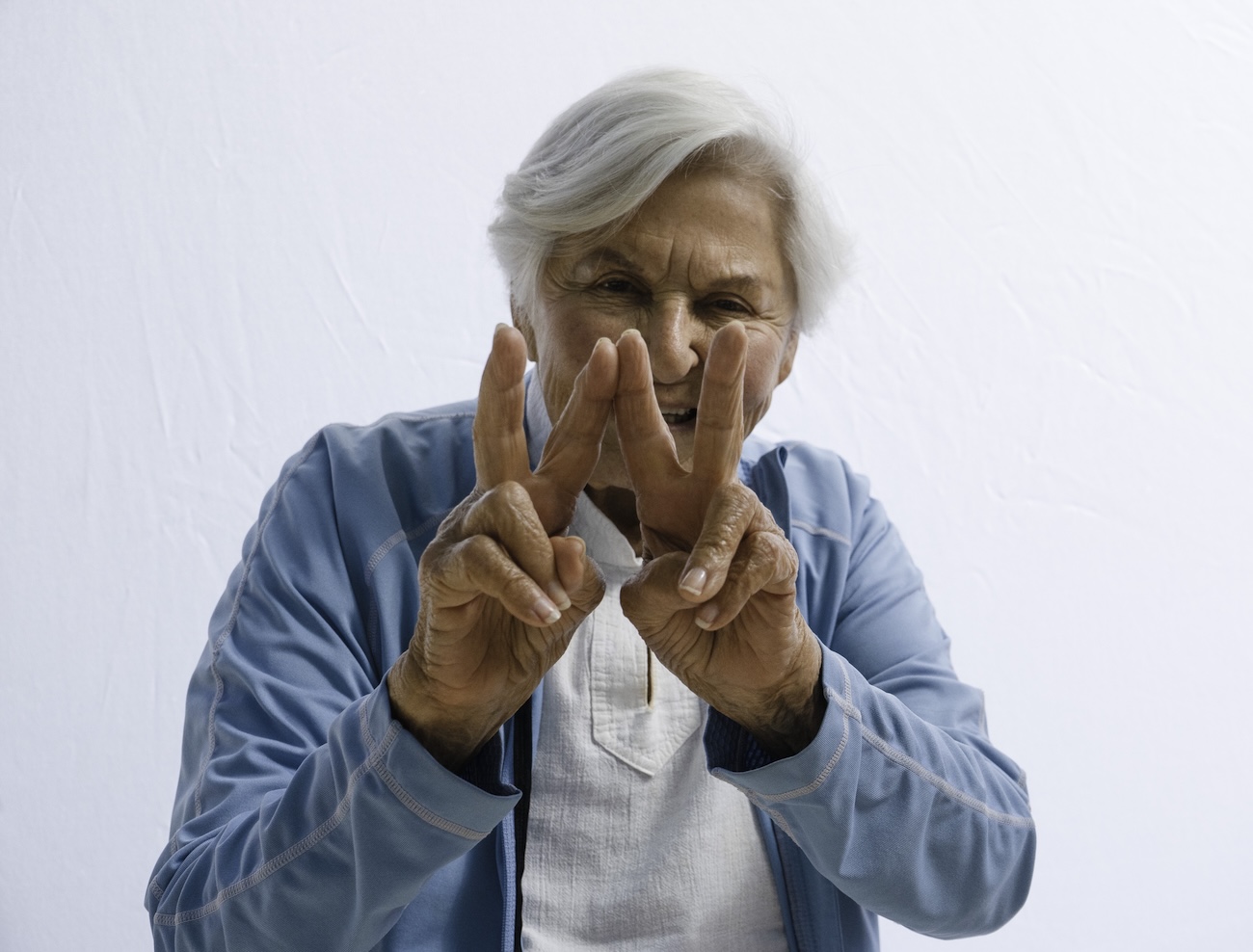 Older lady doing a W sign with her hands and smiling