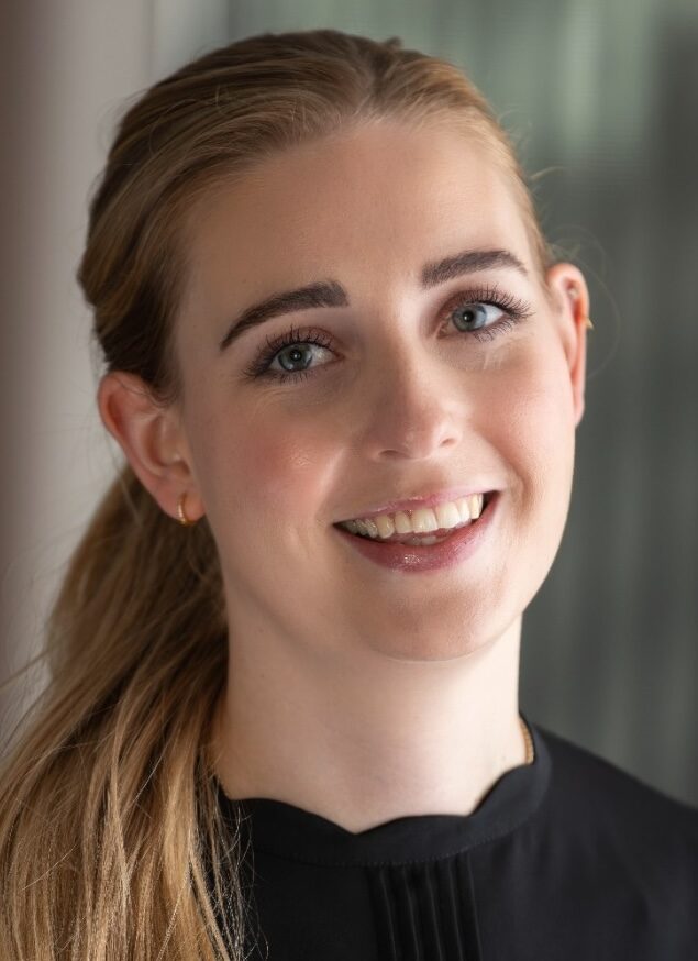 Headshot of smiling lady with dark hair and side ponytail