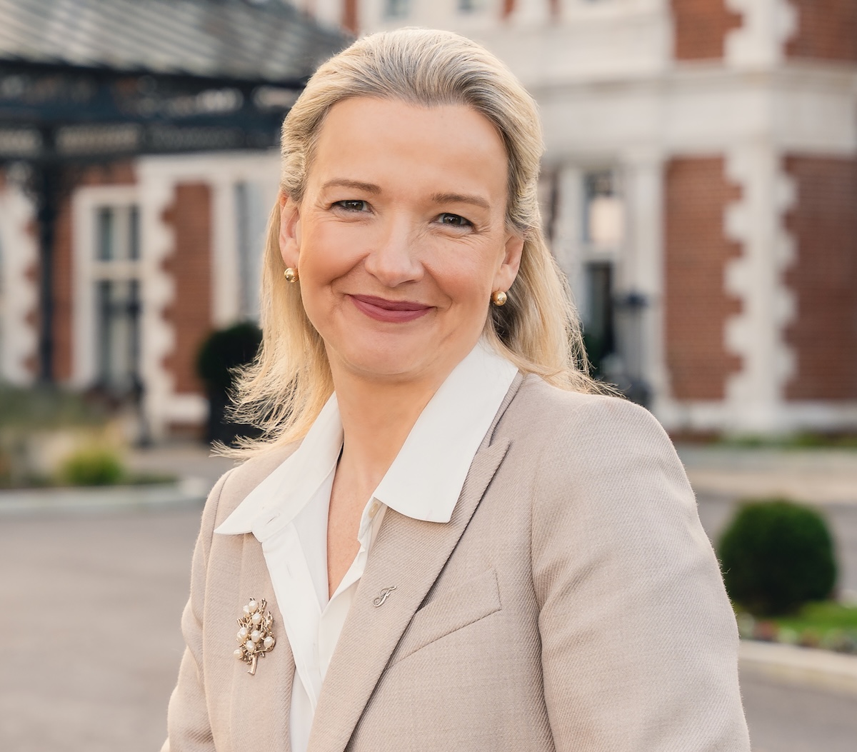 Smiling blonde woman in beige suit jacket and white shirt