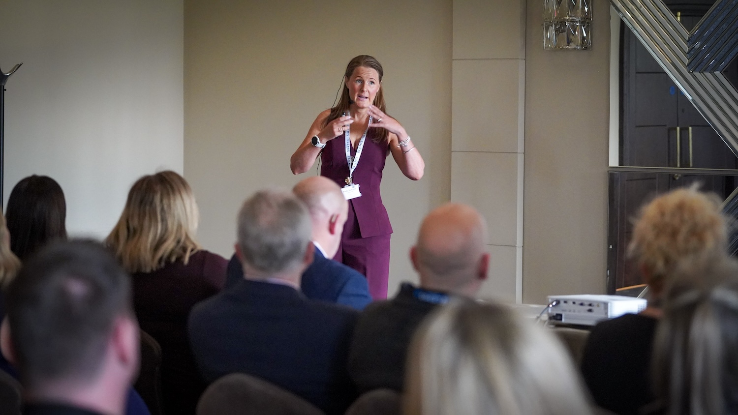 Woman in purple speaking to a room full of event delegates