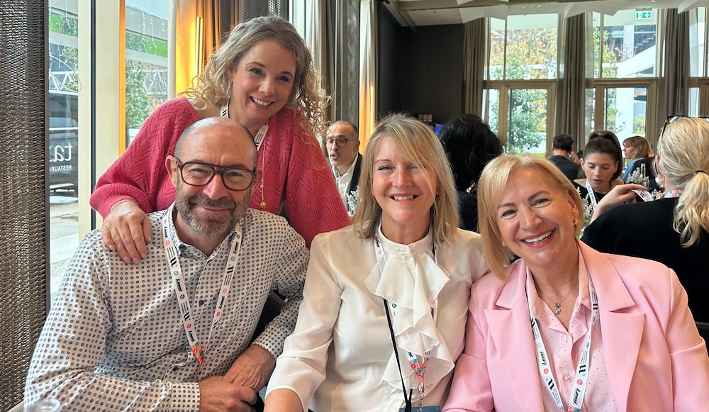 Four people in business attire smiling for the camera