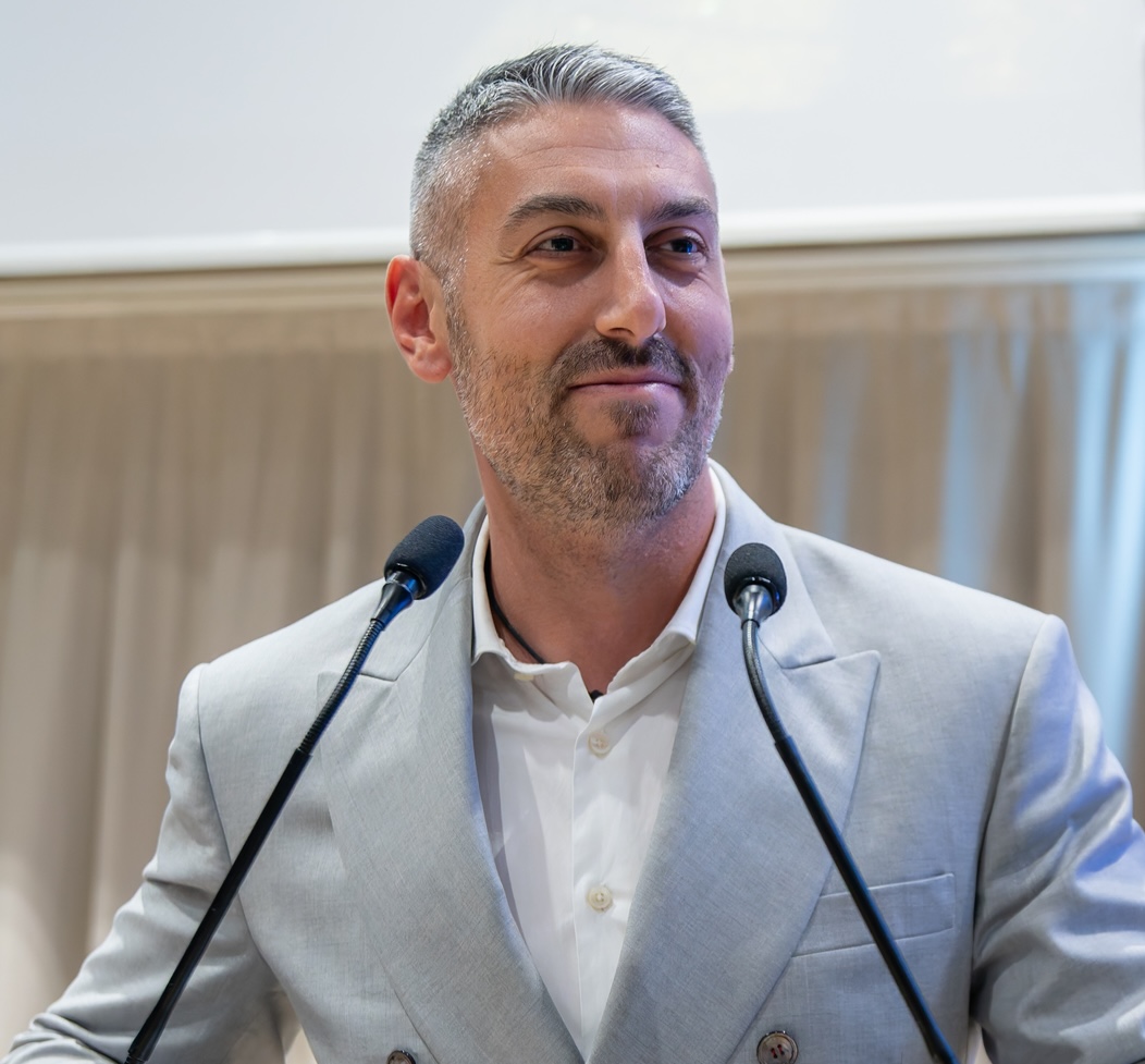 Man doing a presentation stood in front of two microphones