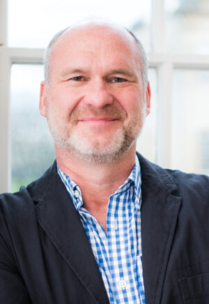 Older man with arms crossed in blue suit and tie