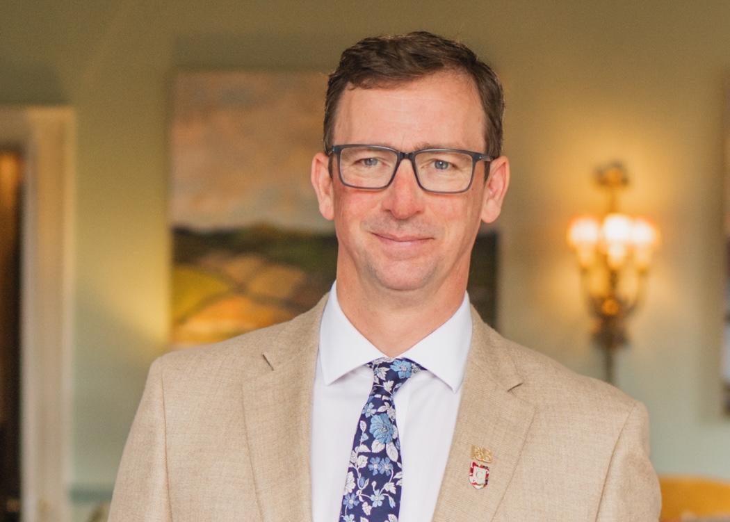 Man wearing glasses in beige suit jacket and tie