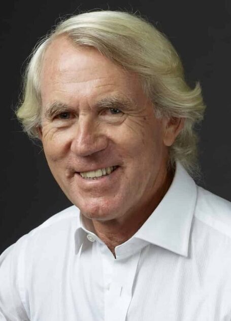 Headshot of man in white shirt with flowing blonde hair