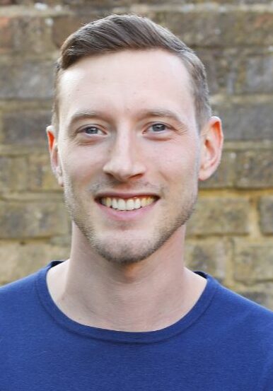Young man in blue jumper posing for picture with his arms crossed
