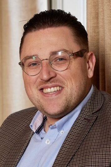 Man in brown suit jacket in glasses sitting on chair