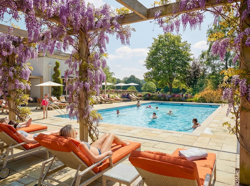 Outdoor pool viewed from under Wisteeria covered pergola