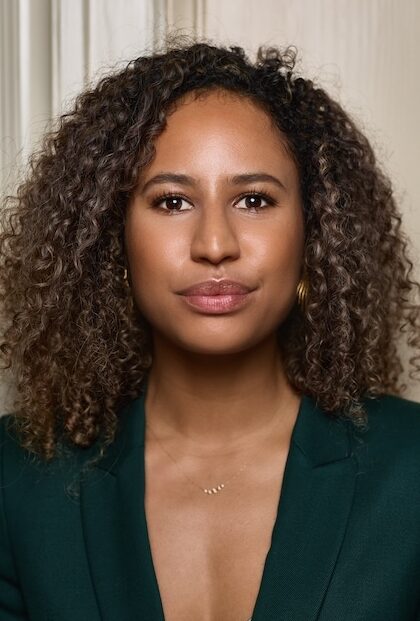 Woman smiling at camera wearing a green tailored suit