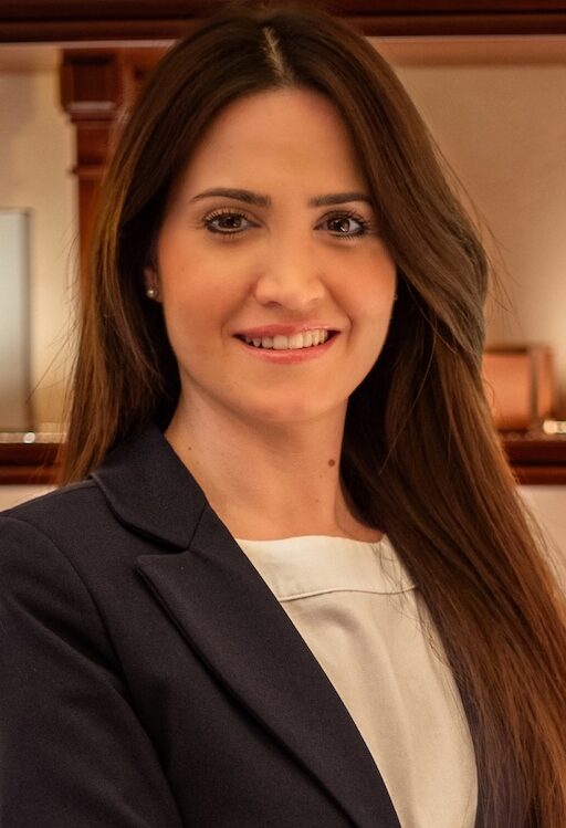 Woman in grey suit with arms folder smiling for the camera