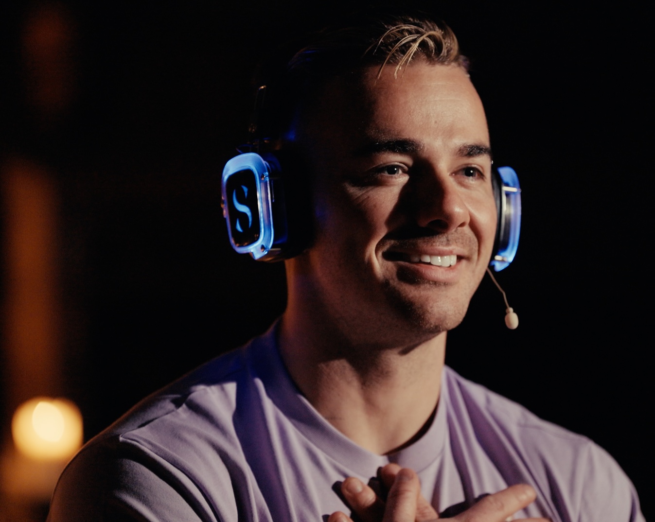 Smiling man in purple tshirt wearing over ear headphones