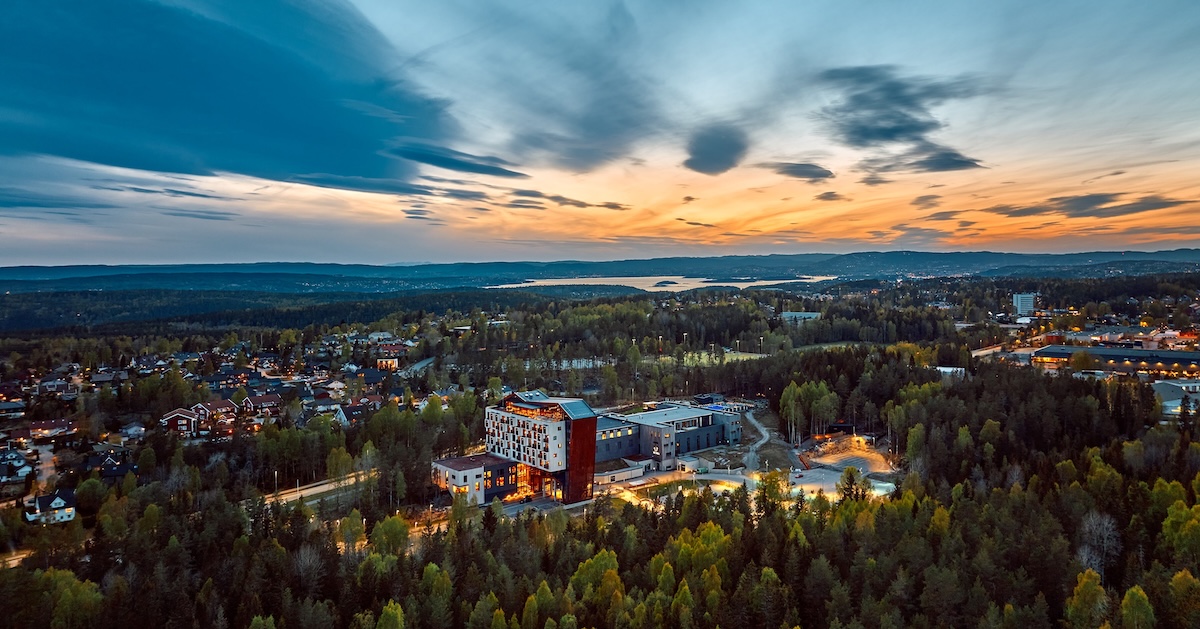 An aerial view of a nordic spa hotel surrounded by woodland at sun rise
