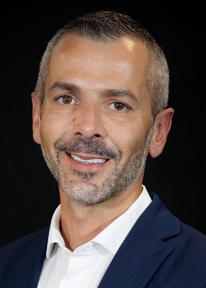 Headshot of man in suit set against black backdrop