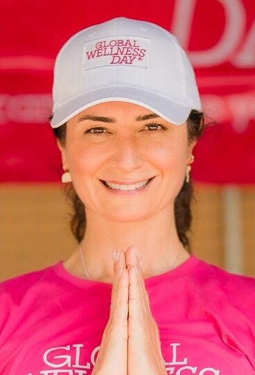 Woman in pink tshirt and white cap making prayer sign