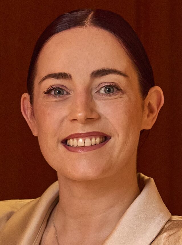 woman in light beige suit with dark hair