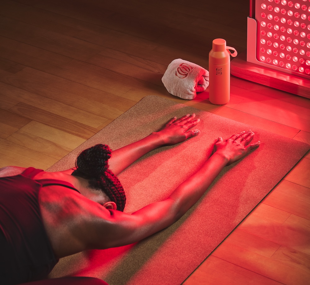 Woman in yoga pose by a red light device