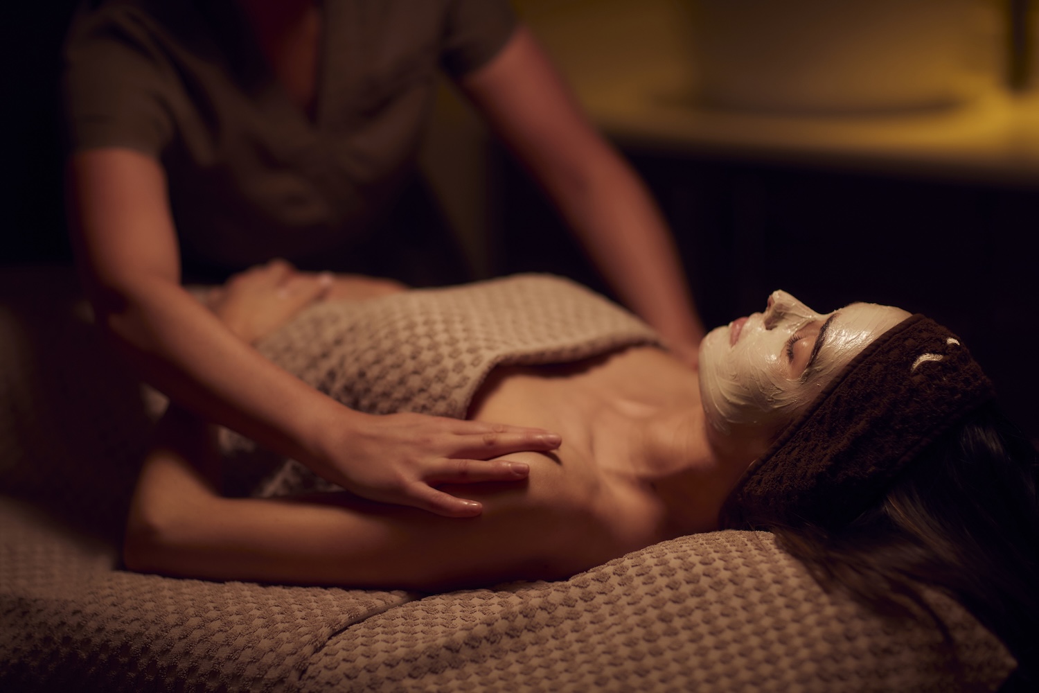Spa therapist giving a woman a face mask treatment.