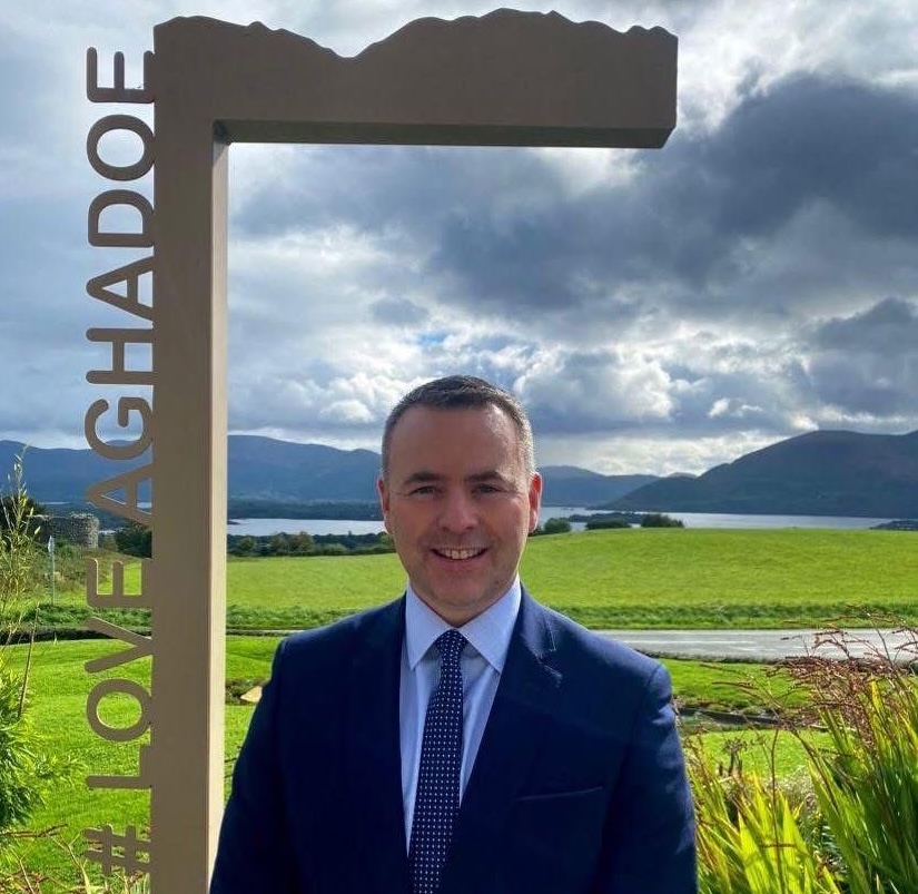 Man stood in front of view of green field and mountains