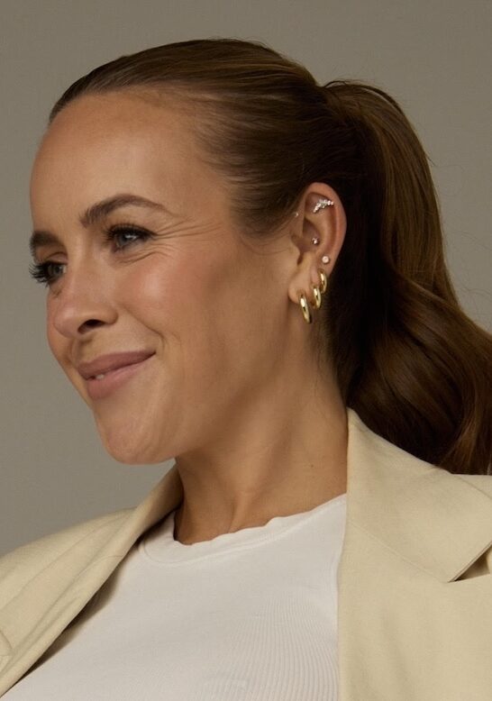 Woman with high ponytail in beige suit and cropped white top