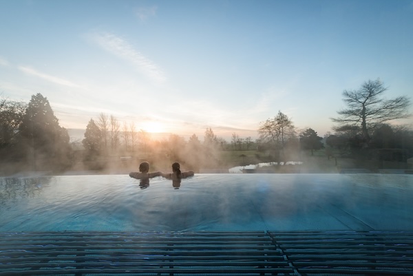 Two people looking across an infinity edge pool at Ragdale Hall