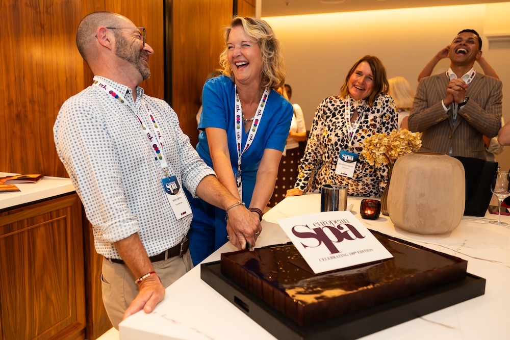 two people laughing and cutting a cake at birthday event