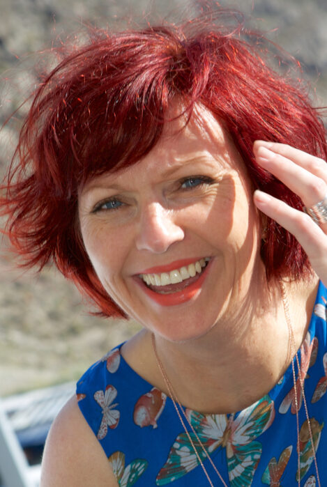 Smiling woman in blue dress with bright red hair