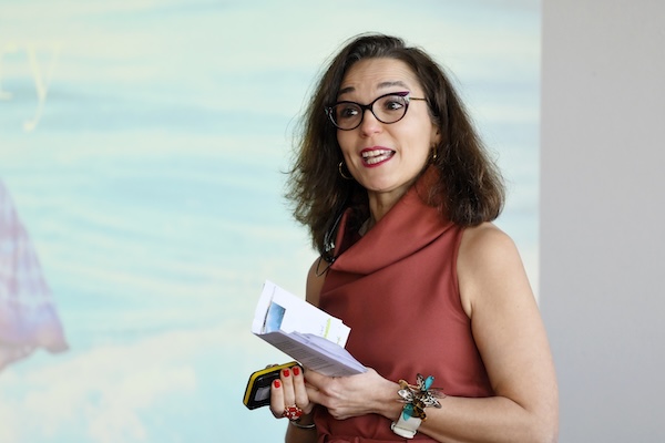 Woman in an orange dress speaking at World Spa and Wellness Convention