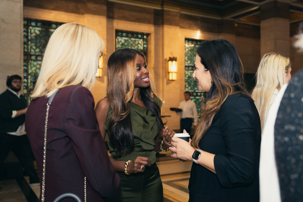 THree women stood talking at a business event