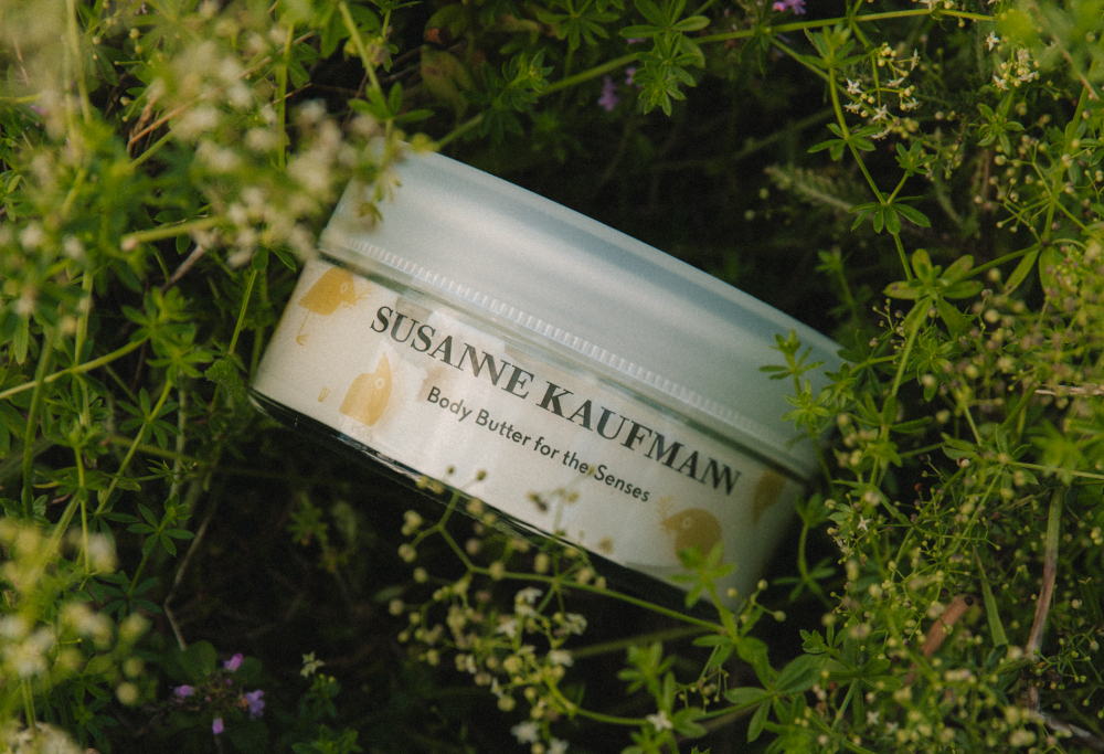 Tub of body butter laid on some moss